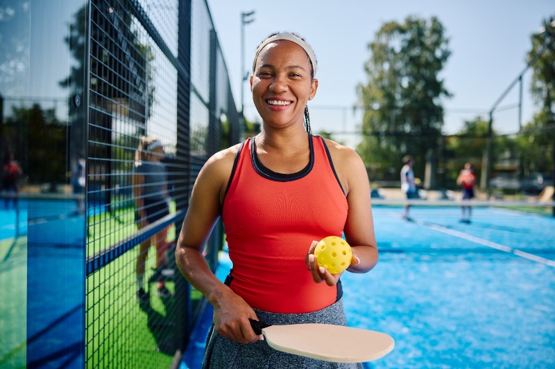 happy-black-woman-with-pickleball-racket-smiling-because-she-has-no-pickleball-back-pain-thanks-to-issi
