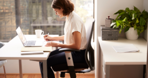 Adult sitting at a desk with forward head posture contrasted with poor posture.