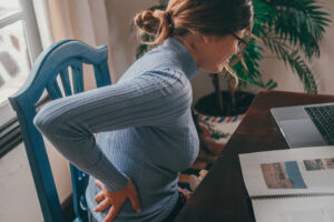Woman with random spine pain while sitting at desk